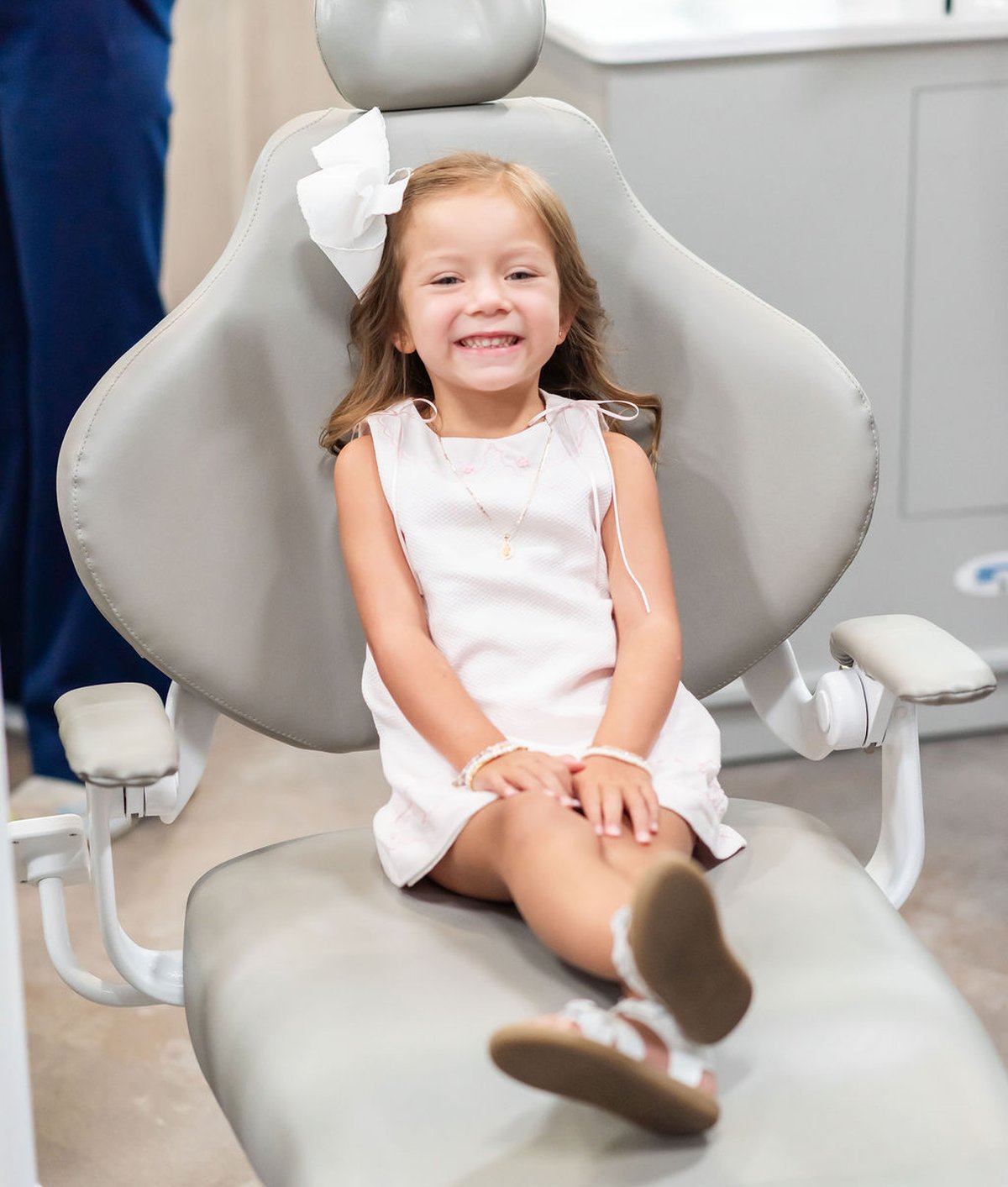 Young patient in a white dress smiling in the dental chair